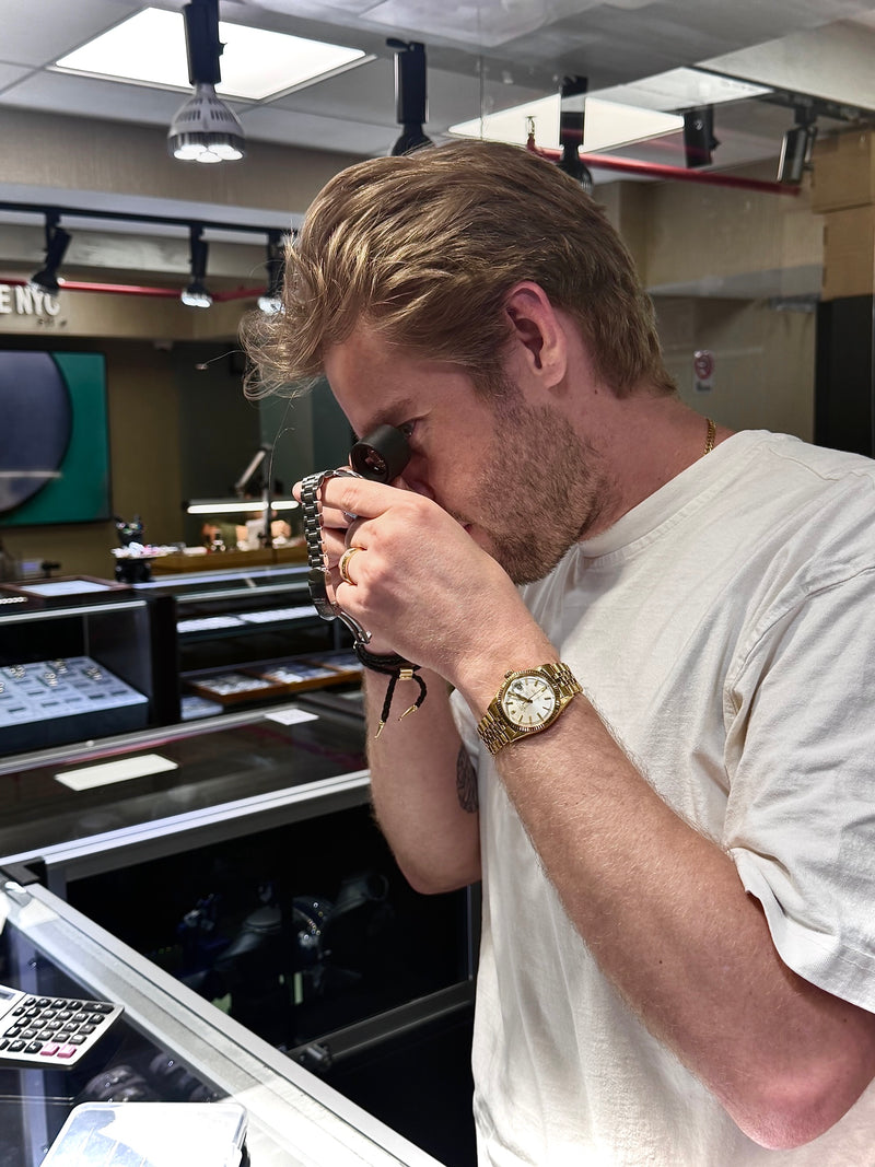 Mathew Arena inspecting a watch with a loupe at the Time To Time Inc. showroom